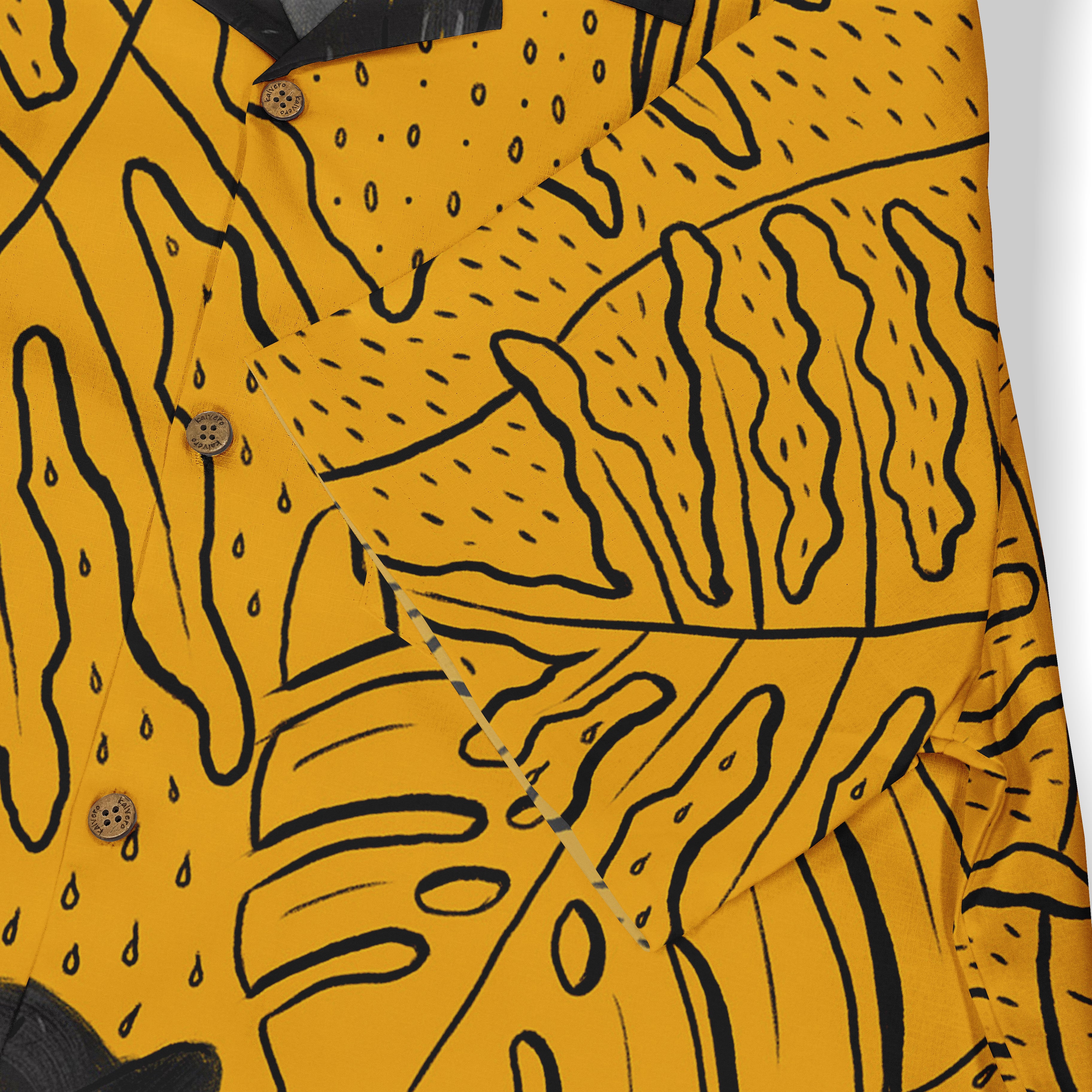 Close-up of a mustard yellow shirt featuring black abstract patterns with bold, curved lines, dots, and organic shapes. The buttons are visible, adding a rustic touch to the design.
