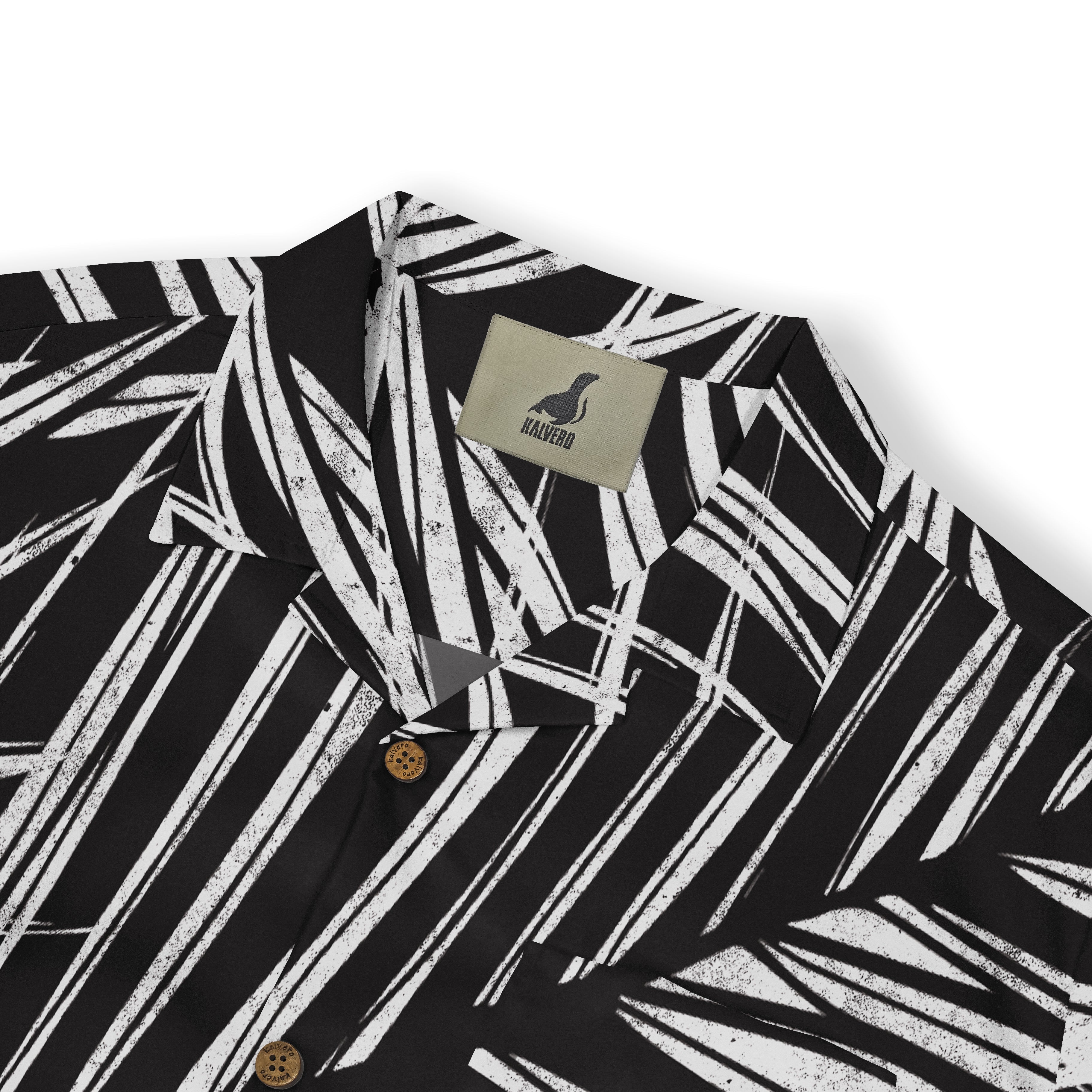 A close-up of a shirt collar featuring a bold white palm leaf pattern on a black background, with a "Kalvero" label visible.