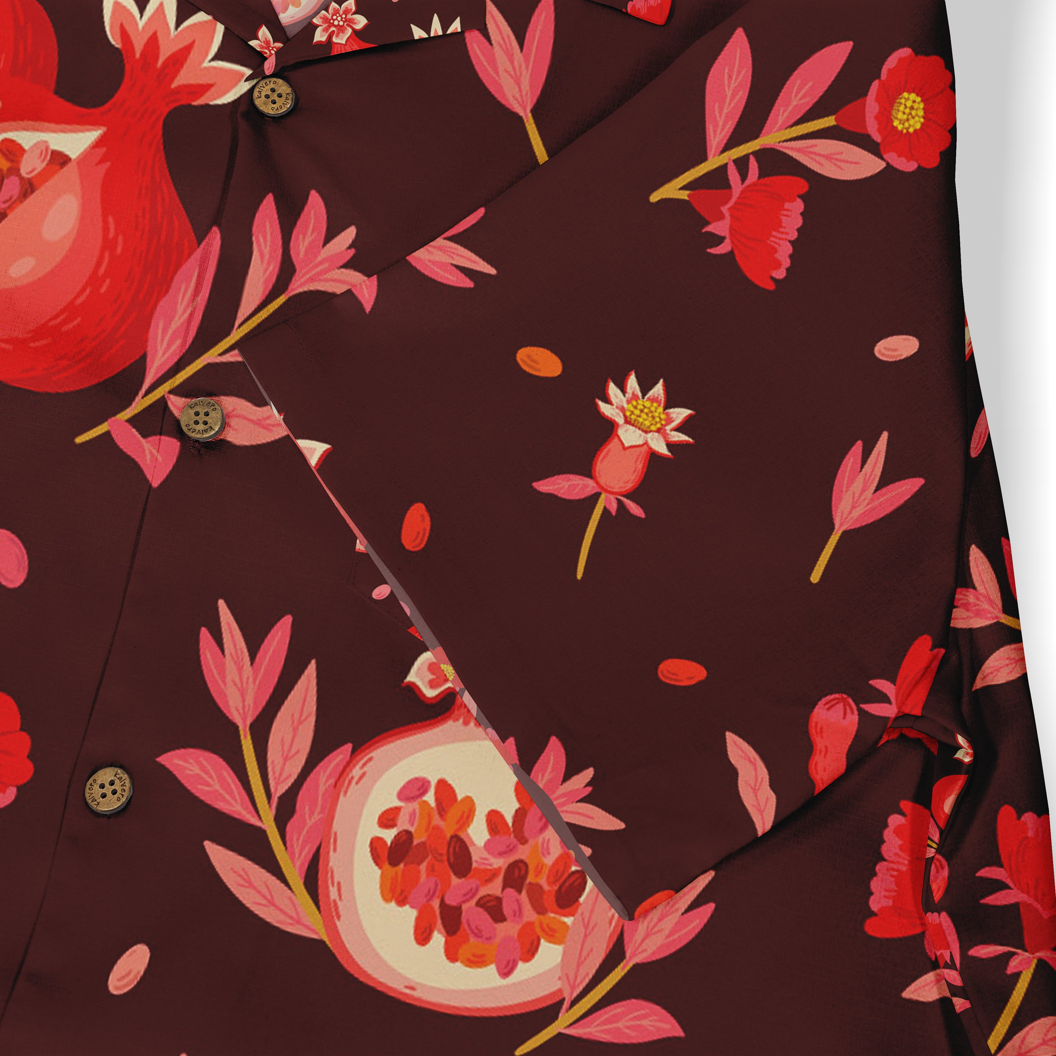 Close-up of a Hawaiian shirt pocket with a pomegranate and floral pattern in red and pink tones on a deep burgundy background, featuring brown buttons.