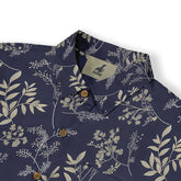 Close-up of a shirt featuring intricate botanical designs on a dark blue background.