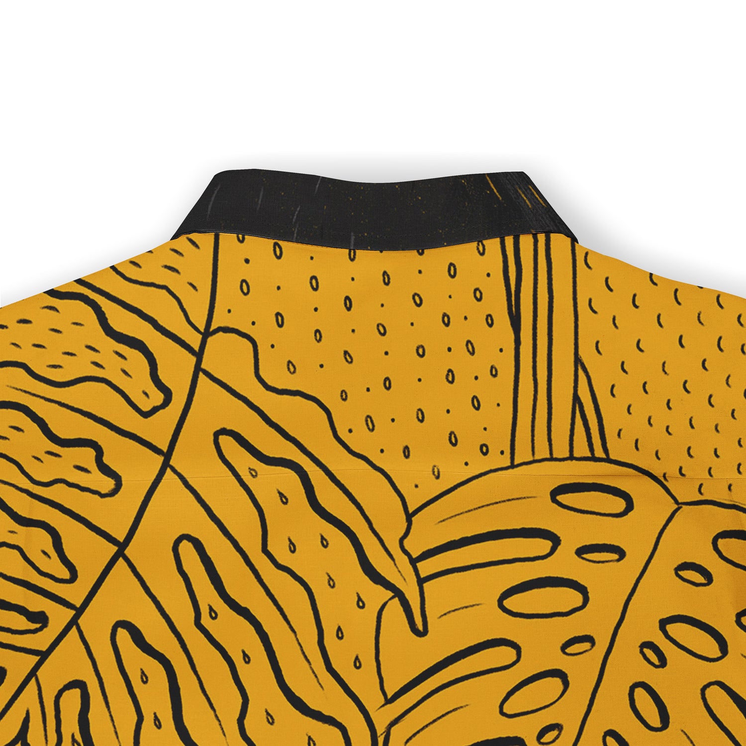 A close-up of a mustard yellow shirt with black abstract patterns, showcasing organic shapes and bold lines. The collar is black, providing a striking contrast against the vibrant background. The design includes wavy and dotted elements, giving it a dynamic, artistic appearance.