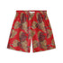 Hawaiian shorts with a vivid red background, featuring large, leopard-print leaves in yellow and brown tones, and subtle snake details.