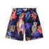 Close-up of tropical-themed shorts with vibrant designs featuring a parrot, leopard, monkey, and lush foliage in shades of purple, red, and blue on a dark background.