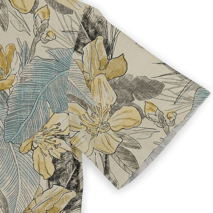 Close-up of a Hawaiian shirt sleeve featuring a floral design with yellow flowers, blue leaves, and subtle black accents on a beige background, emphasizing the shirt&