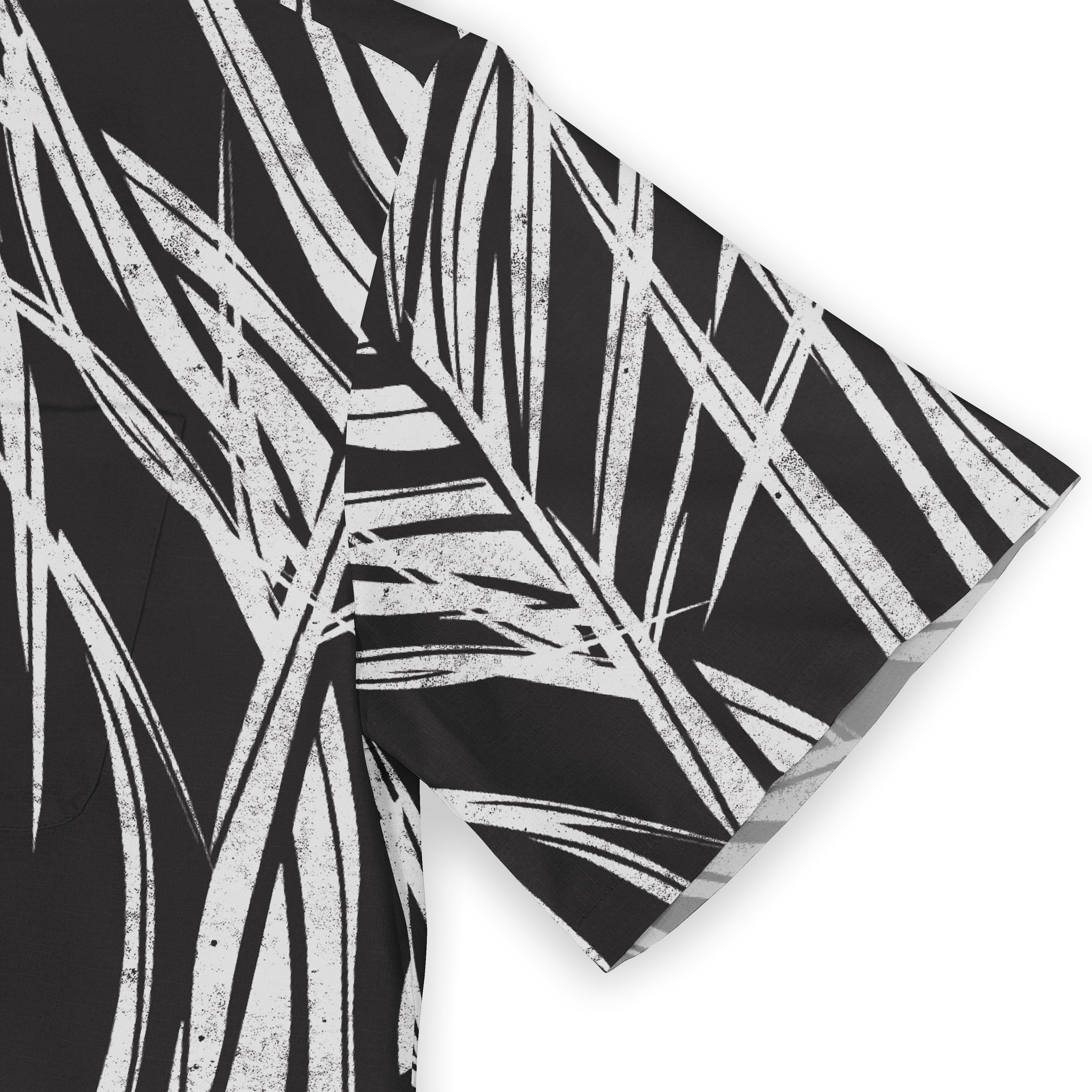 A shirt sleeve with a bold white palm leaf pattern on a black background, showcasing a striking monochrome design.