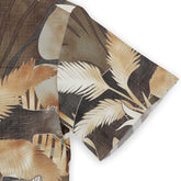 Close-up of a Hawaiian shirt sleeve with a jungle-themed design, featuring palm leaves in earthy tones.