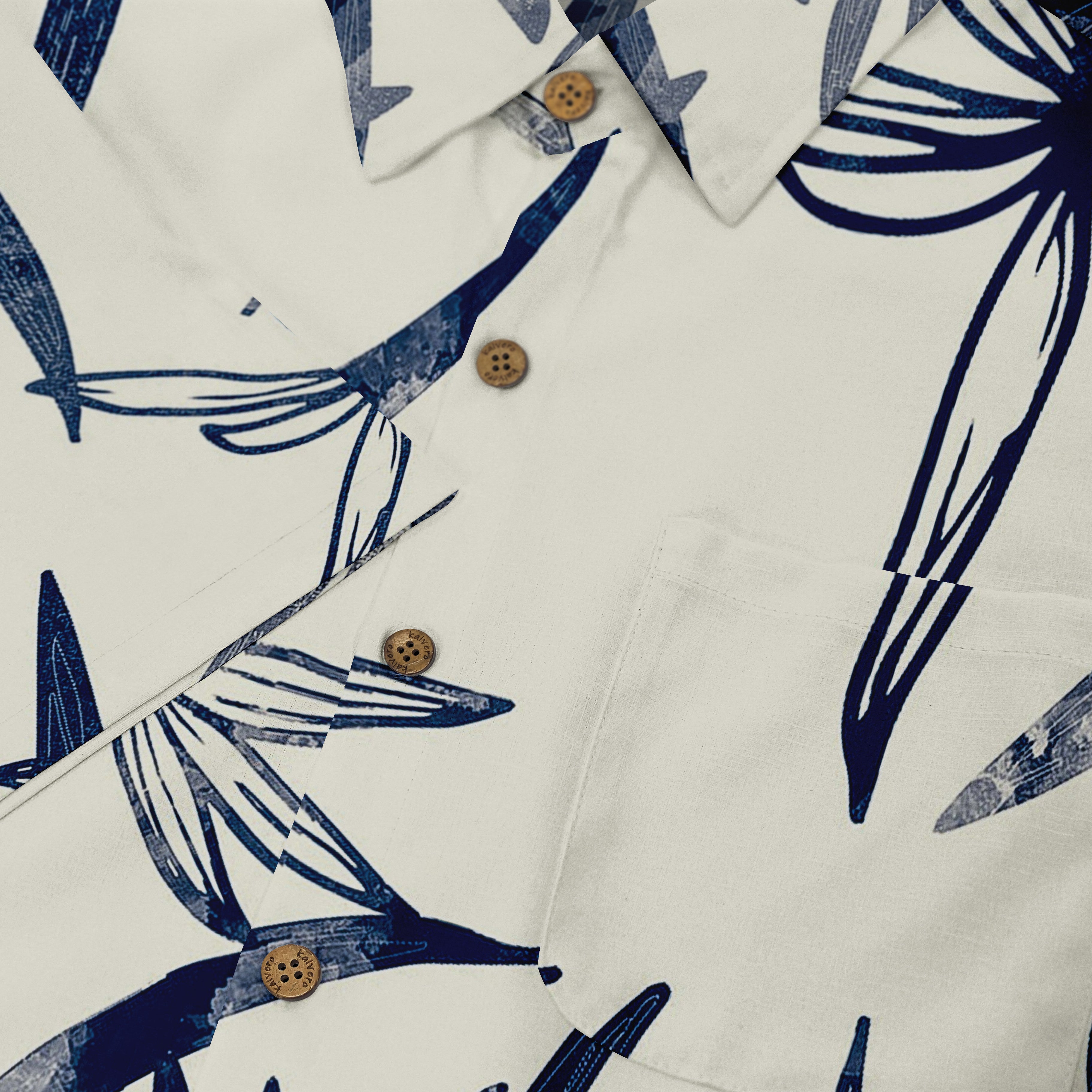 A detailed close-up of a shirt with an abstract floral pattern in dark blue on a white background, featuring wooden buttons and a front pocket, highlighting its minimalist yet elegant design.