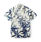 xA short-sleeved shirt featuring a striking design of abstract floral and leaf patterns in deep blue hues against a clean, white background, perfect for a modern and stylish look.